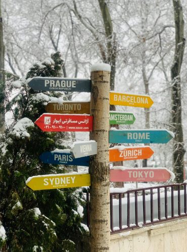 pexels-photo-3600096-3600096 Colorful signpost displaying international city names against a snowy background.